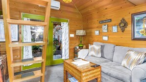 Ein gemütliches Zimmer mit Holzvertäfelung, einer grünen Tür, einem Sofa, einem Couchtisch und einem an der Wand befestigten Schild mit der Aufschrift 'New Orleans'.