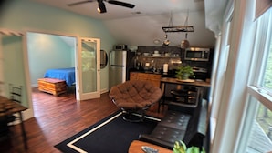 Un espacio habitable compacto con kitchenette, zona de comedor y sala de estar con sofá y sillón.