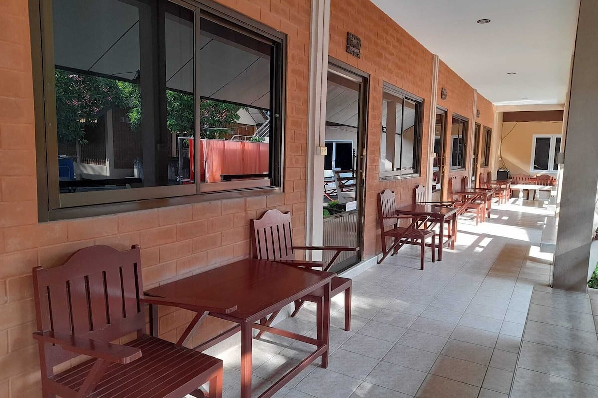 A covered outdoor seating area with brick walls and large windows.