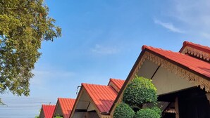 A row of traditional-style buildings with red roofs and wooden balconies, surrounded by well-maintained greenery. - Sukthawee (Prachuap Khiri Khan)