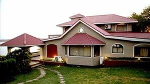 Une maison à deux étages avec un toit rouge, un porche abrité et un petit jardin agrémenté d’un chemin en pierre.