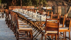Une rangée de tables et de chaises en bois, disposées à l’extérieur, probablement pour les repas.