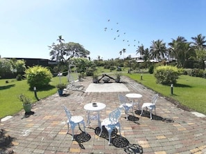 An outdoor patio with white metal chairs and tables, surrounded by greenery and palm trees. - Wei Feng Jia Yuan B&B (Taitung)