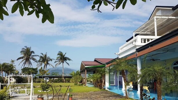 Un complexe hôtelier doté d’une piscine, de palmiers et d’un patio couvert.