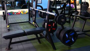 Een fitnessruimte met gewichthefapparatuur, een bank en een spiegel.