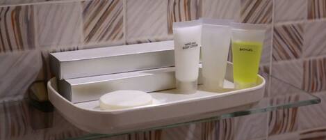 A bathroom shelf with toiletries including hand and body lotion, bath gel, and a soap bar.