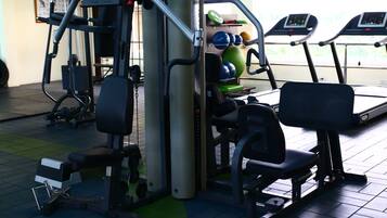 A gym with exercise equipment, treadmills, and a green mat area.