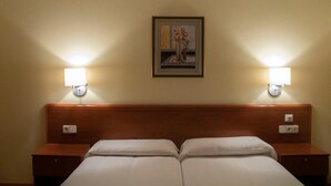 Een hotelkamer met een tweepersoonsbed, twee nachtkastjes en twee wandlampen.