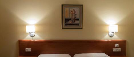 Habitación de hotel con cama doble, dos mesitas de noche y dos lámparas de pared.