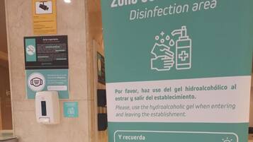 A sign in a hotel lobby indicating a disinfection area and instructions for using hydroalcoholic gel.