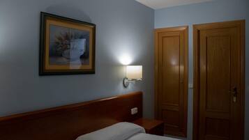 Een hotelkamer met een bed, een nachtkastje, een wandlamp en twee houten deuren.