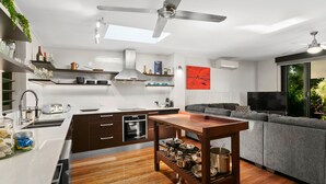 A modern kitchen with a central island, built-in oven, and a dining area with a wooden table. - Tropical 3 Bedroom House, Pool plus 4th Bedroom Bungalow (Whitfield)