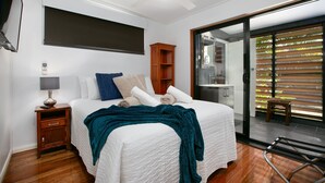A bedroom with a bed, a nightstand, a wooden cabinet, and a sliding glass door to a balcony. - Tropical 3 Bedroom House, Pool plus 4th Bedroom Bungalow (Whitfield)