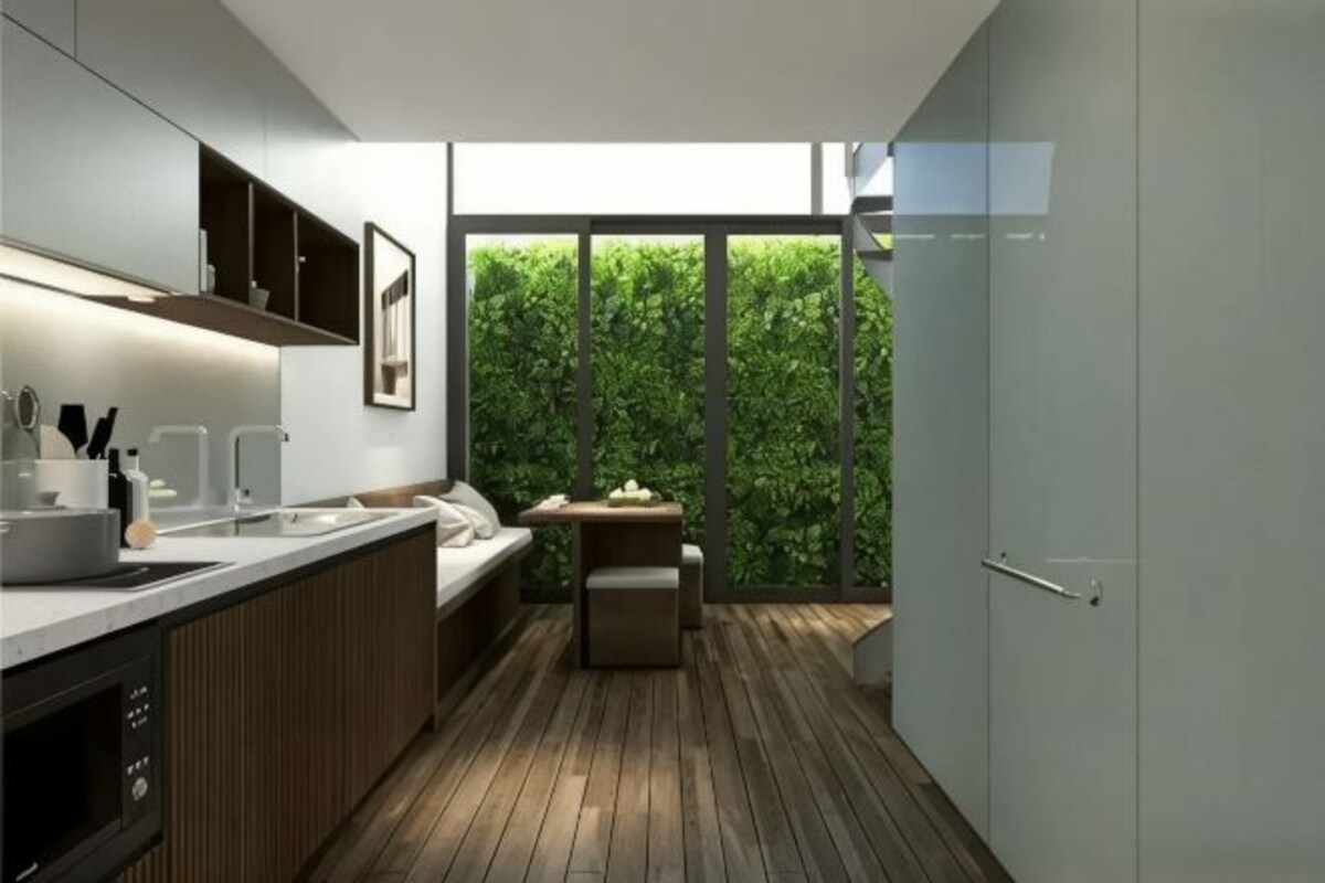 Une cuisine moderne avec un plancher en bois, un four encastré et une grande fenêtre donnant sur un espace verdoyant.