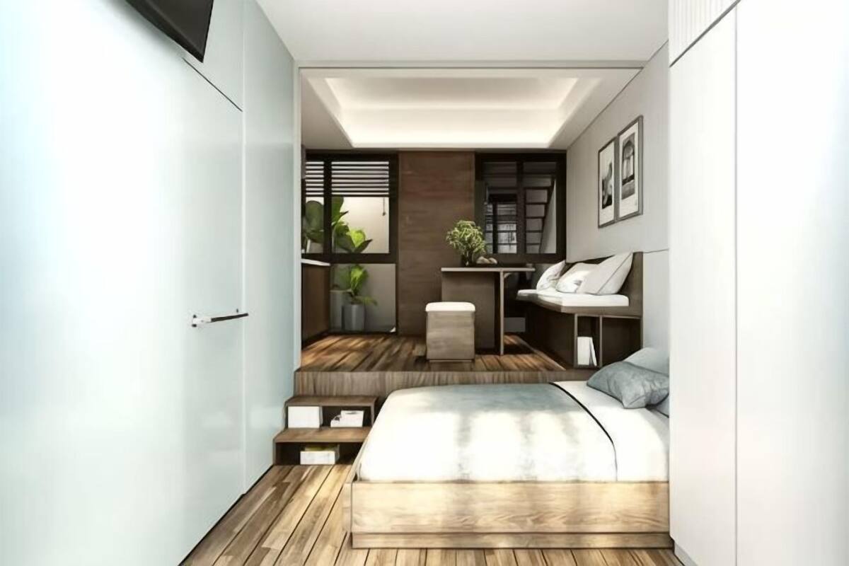Un dormitorio pequeño con cama, mesita de noche y un rincón de escritorio con silla.
