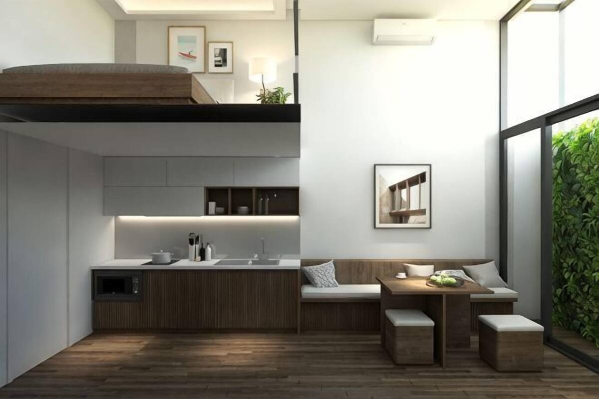 Una cocina moderna con una isla integrada, una zona de comedor con banco y un amplio ventanal con vistas a zonas verdes.