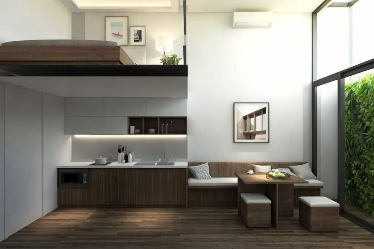 A modern kitchen with a built-in island, a dining area with a bench, and a large window offering a view of greenery.