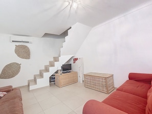 A living room with a staircase, a red sofa, a television, and a small table. - N&J - MAISON COURNICHEE- Central - Very close sea (Niza)