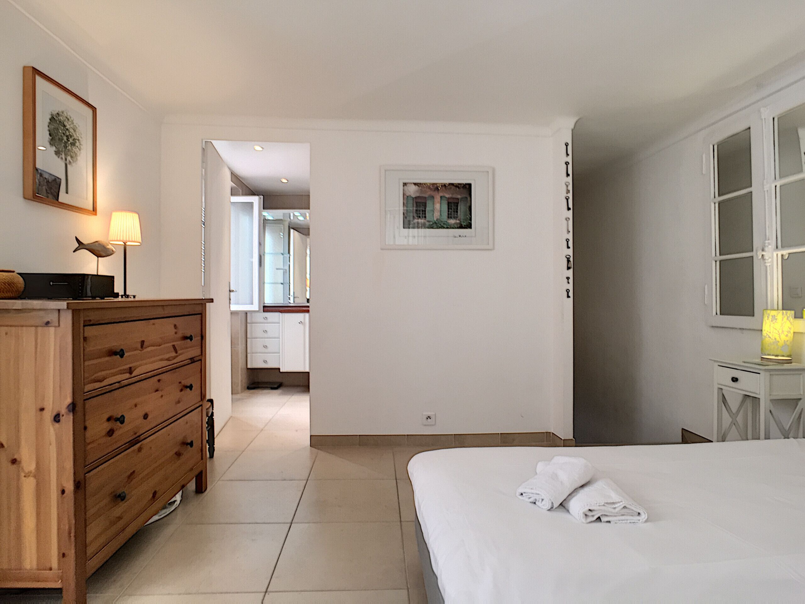 Hotellihuone, jossa on sänky, puinen lipasto, työpöytä ja seinällä oleva kehystetty kuva.