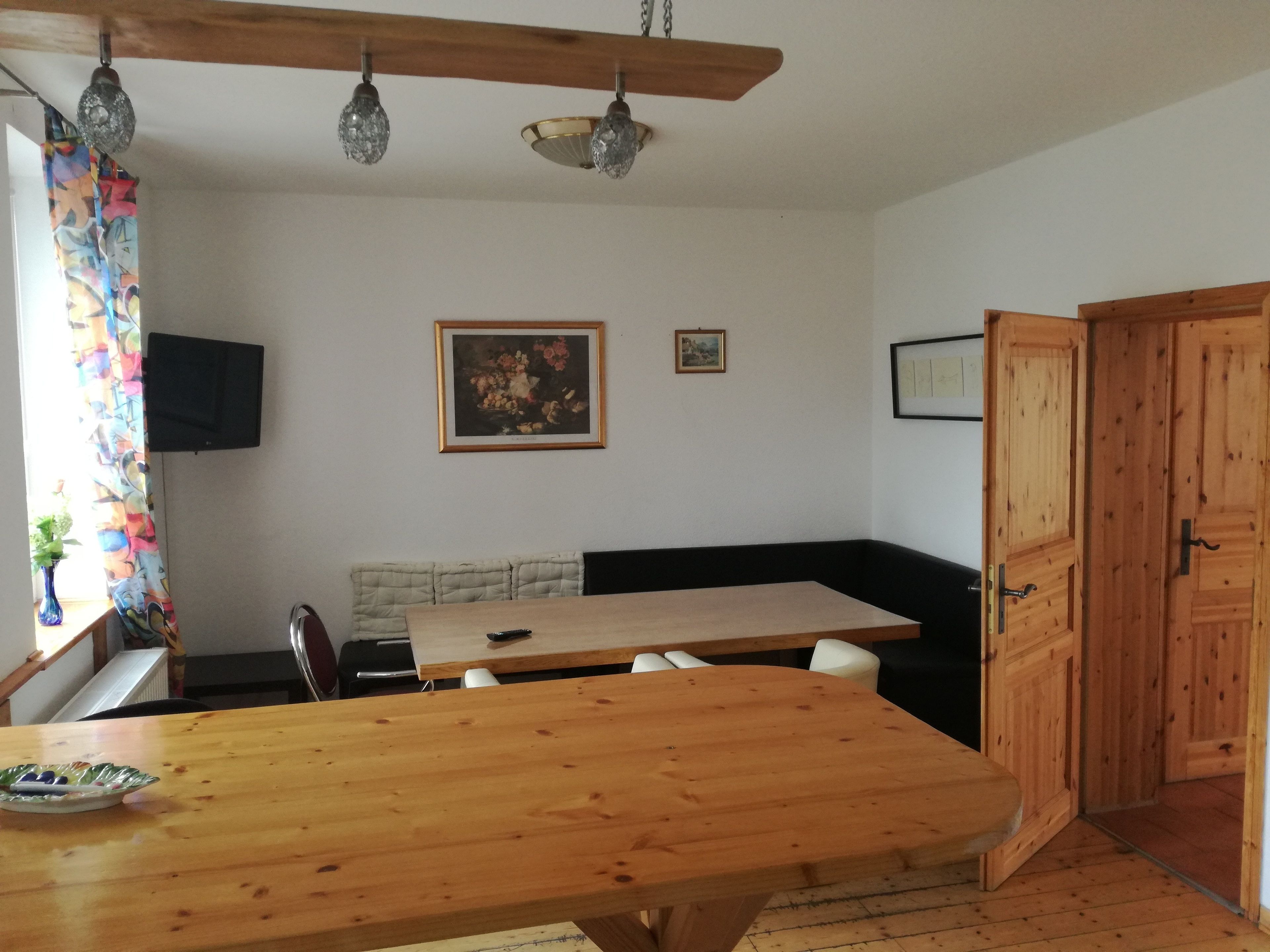 A dining area with a wooden table, chairs, a black cushioned bench, and a wooden door.