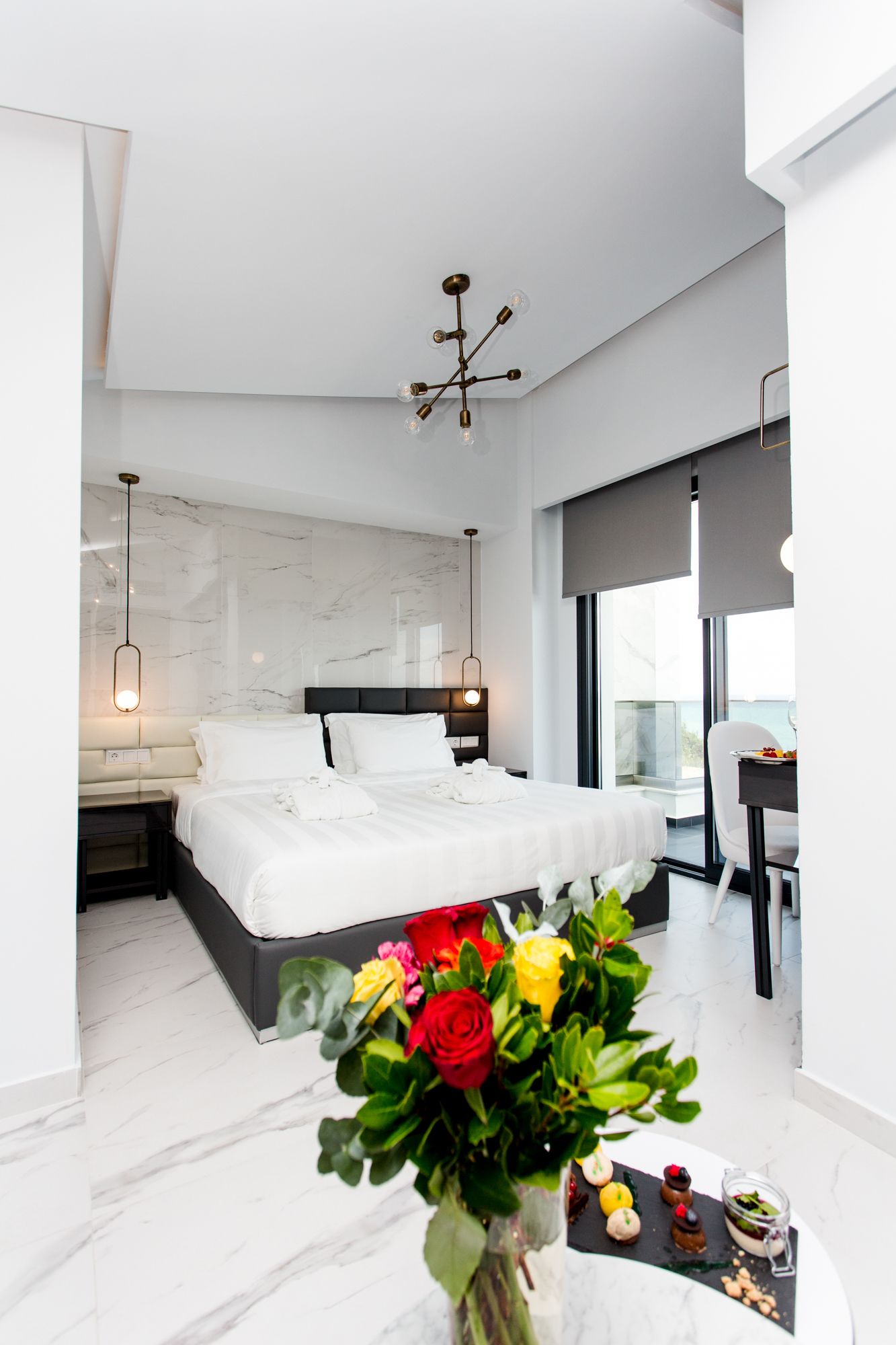Una habitación de hotel moderna con una cama grande, un escritorio con una silla y un balcón con vistas.
