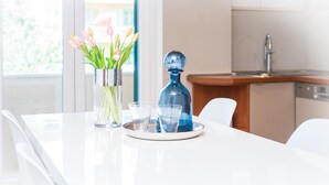 A modern kitchen with a white countertop, a vase with tulips, and two glasses. - Apartment Franco (Split)