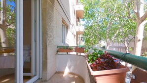 A balcony with potted plants, a sliding glass door, and a view of a tree and buildings. - Apartment Franco (Split)