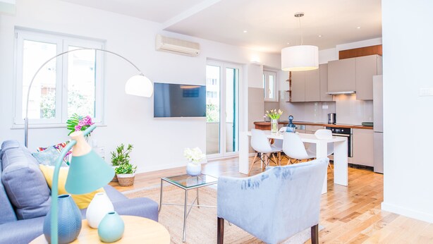 A modern living room with a sofa, a coffee table, and a TV. There is a kitchen area with cabinets and a dining table. - Apartment Franco (Split)