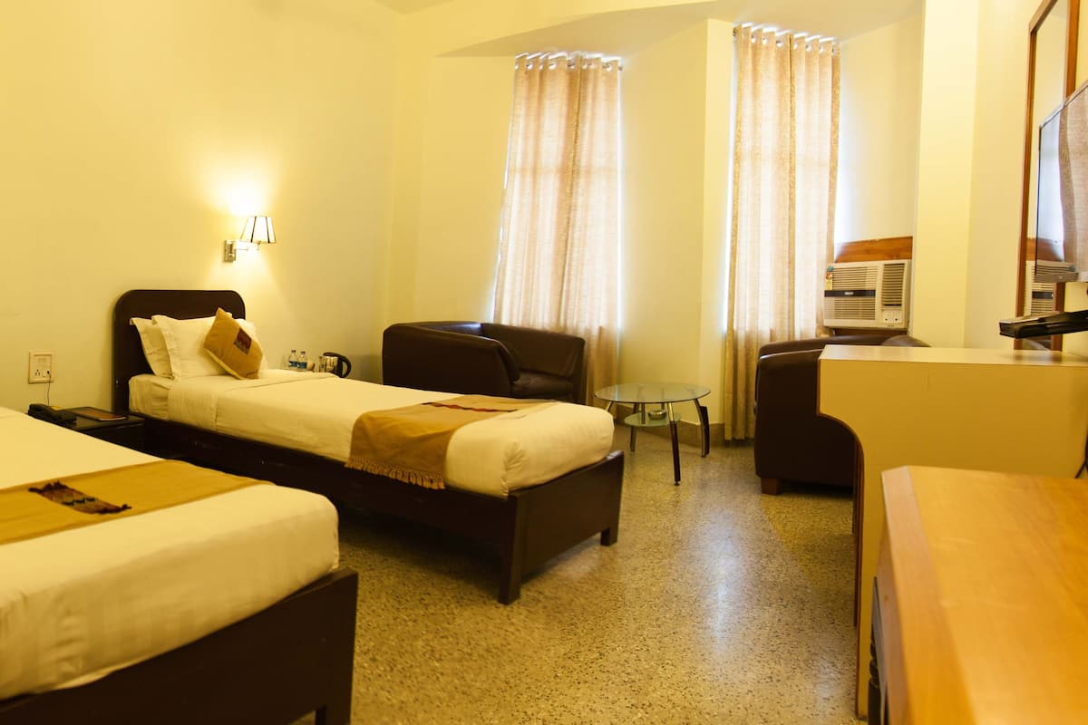 Une chambre d’hôtel avec deux lits, un bureau, une chaise et un téléviseur.