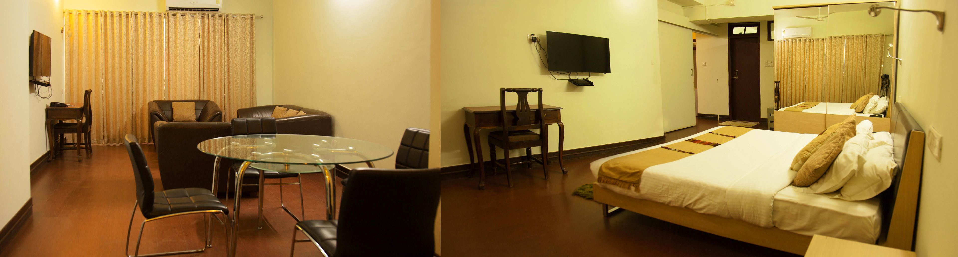 Een hotelkamer met een bed, een bureau, een stoel, een glazen tafel, een televisie en een badkamer.