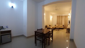 A spacious living area with a dining table and chairs, a sofa set, and a small kitchenette. - Hotel Saramati (Dimapur)