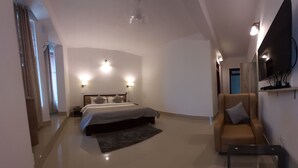 A modern bedroom with a bed, a sofa, a TV, and a flat-screen TV mounted on the wall. - Hotel Saramati (Dimapur)