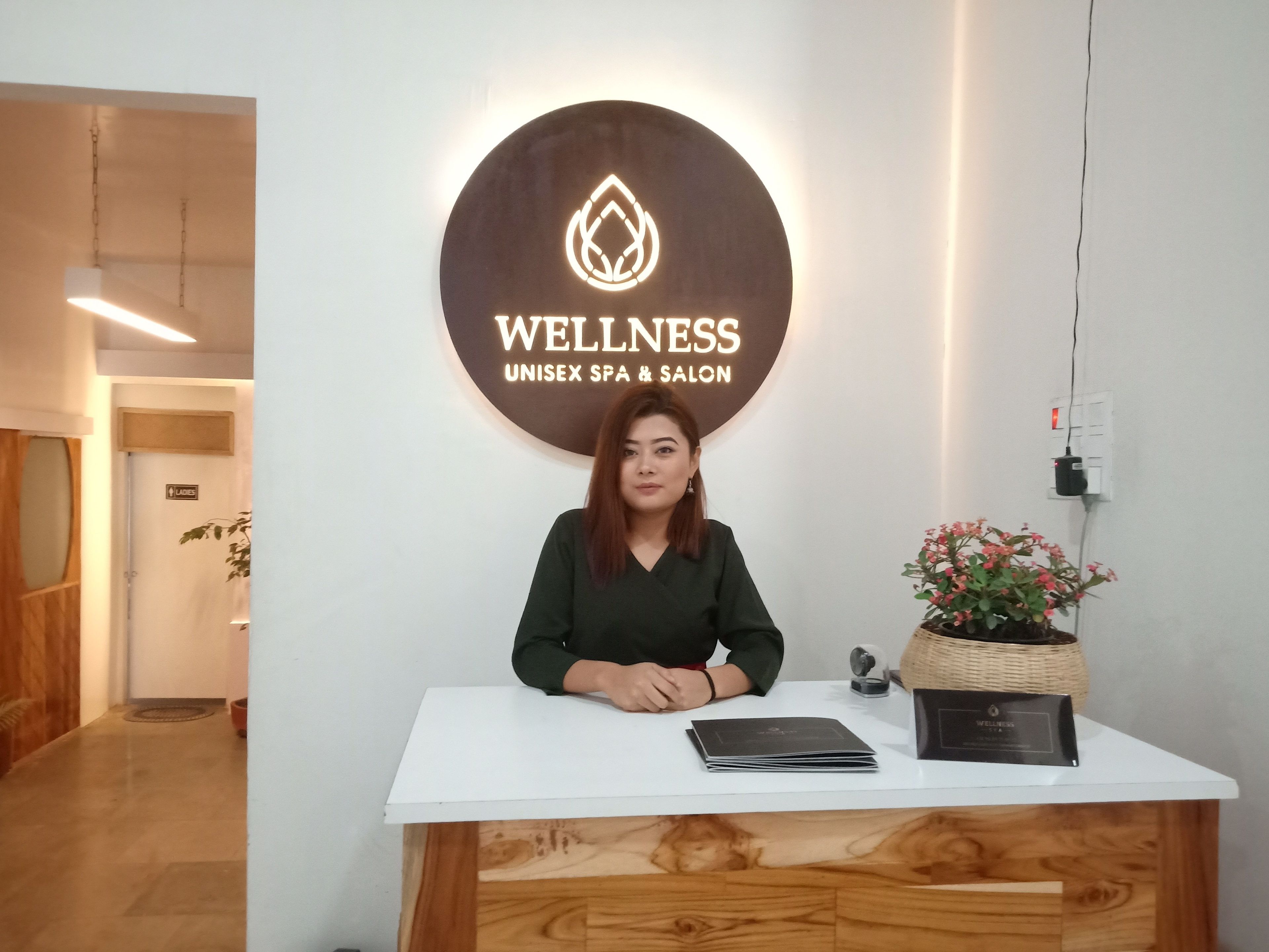 A reception desk with a sign reading "WELLNESS UNISEX SPA & SALON".