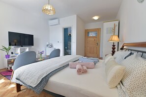 A bedroom with a bed, bedside tables, a TV, a desk, and a door. - Harmony Room Hvar (Hvar)