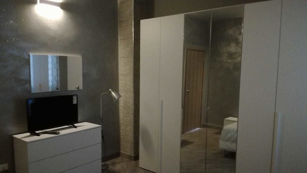 Un dormitorio con un armario, un espejo y una mesita de noche.