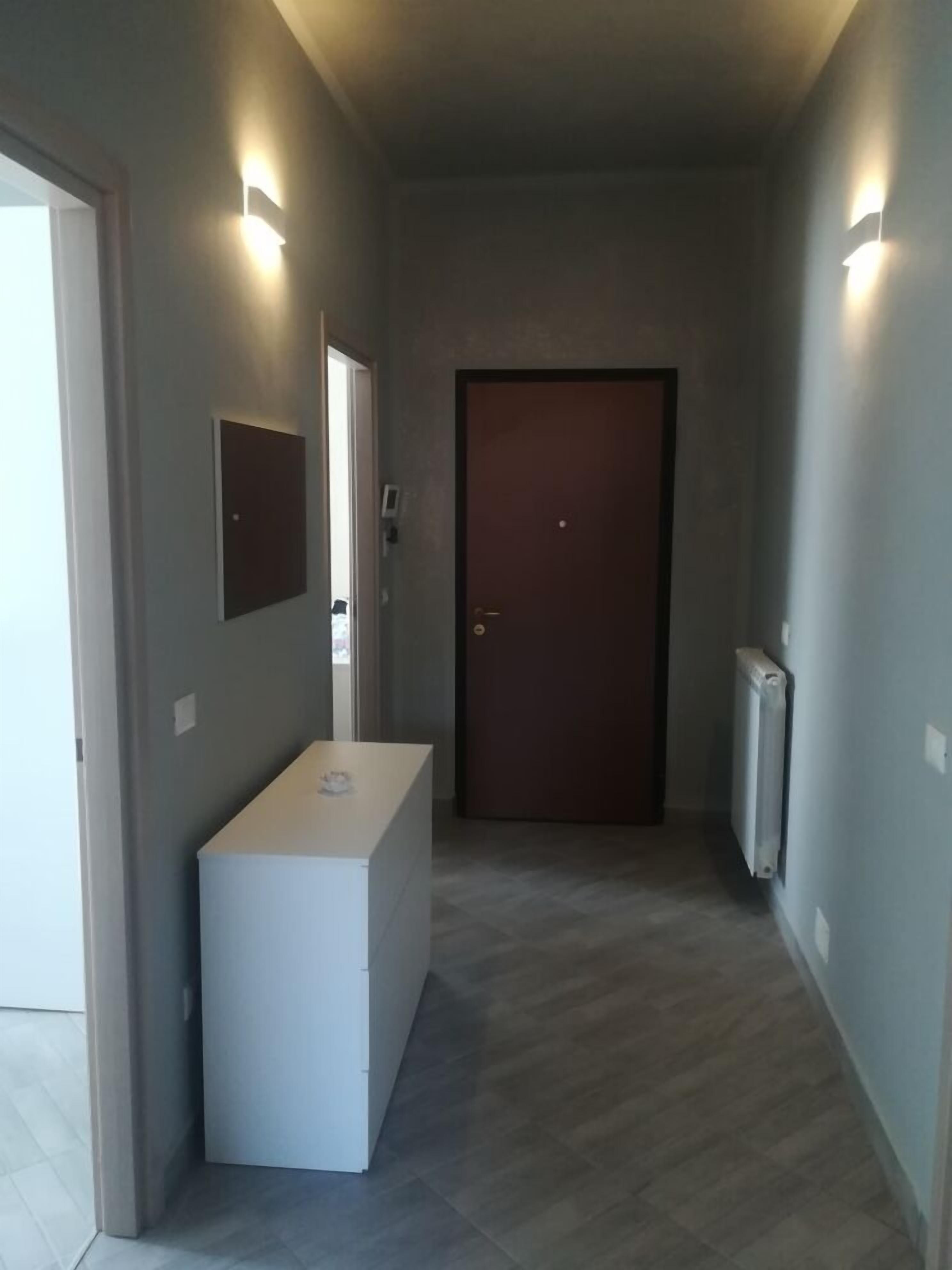 A hallway with a white reception desk, a door at the end, and a radiator on the wall.