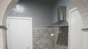 Un baño pequeño con una puerta blanca, un mueble blanco y una pared con diseño de piedra.