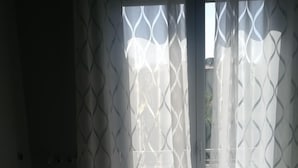 Un lavadero con lavadora, secadora y un amplio ventanal con cortinas estampadas.