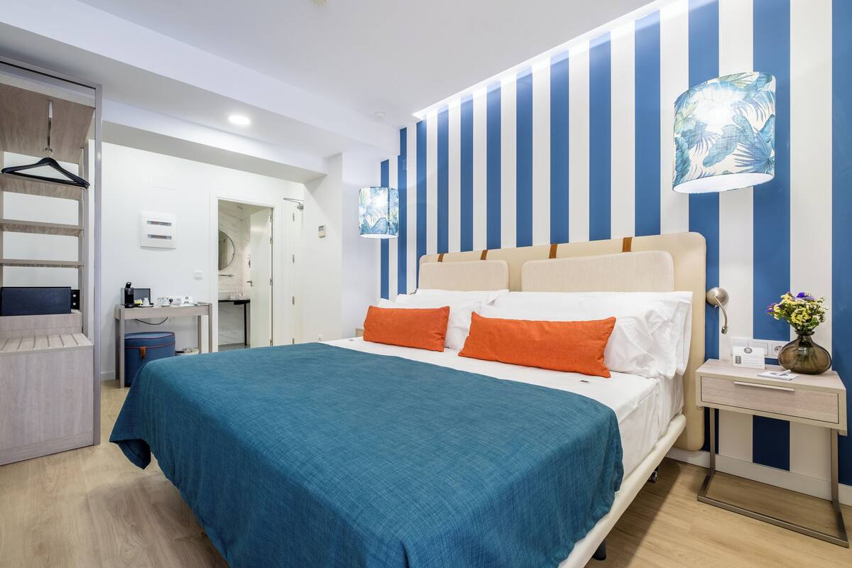 A hotel room with a bed, a desk, and a wardrobe.