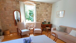 A cozy room with stone walls, a wooden table with a key, a potted plant, and a sofa. - Historic Piazza House & Romantic Garden (Hvar)