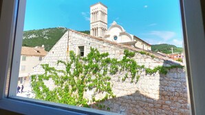 A stone building with a bell tower, surrounded by greenery and a clear sky. - Historic Piazza House & Romantic Garden (Hvar)