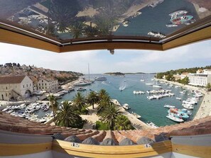 A panoramic view of a marina with numerous boats docked, palm trees, and buildings along the waterfront.