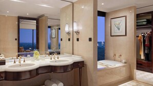 A luxurious bathroom with a large vanity, dual sinks, a bathtub, and a view of the cityscape.