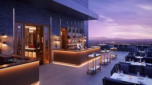 A rooftop bar with a bar counter, seating area, and a view of the cityscape at dusk. - The Ritz-Carlton, Pune (Pune)