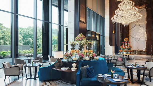 A spacious lobby with a blue sofa, round tables, and a chandelier. - The Ritz-Carlton, Pune (Pune)