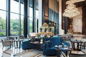 A spacious lobby with a blue sofa, round tables, and a chandelier. - The Ritz-Carlton, Pune (Pune)