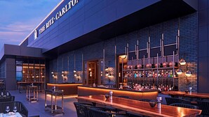 An outdoor bar area with a wooden table and chairs, a bar counter with bottles, and a sign reading "THE RITZ-CARLTON". - The Ritz-Carlton, Pune (Pune)