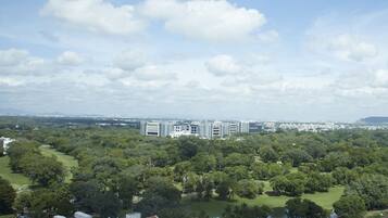 An aerial view of a cityscape with modern buildings, a park with a lake, and a clear sky.