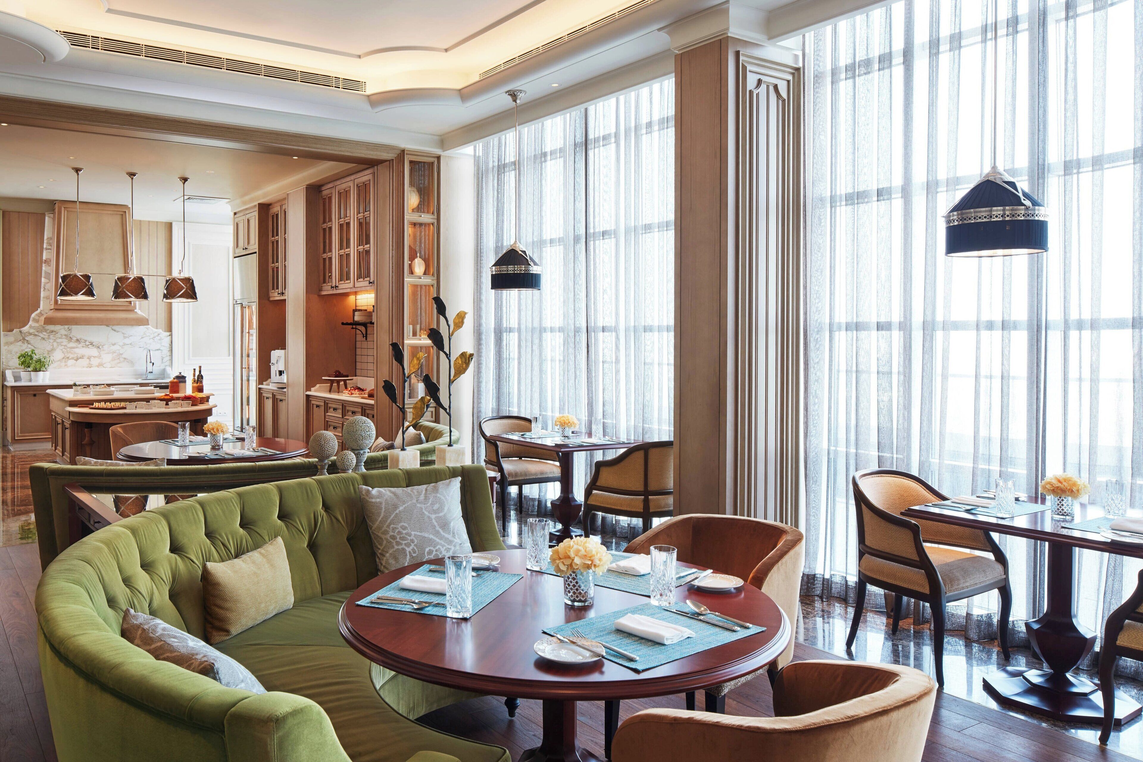 A spacious dining area with a round table, chairs, and a green sofa.