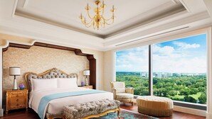 A spacious bedroom with a large bed, a chandelier, a view of a cityscape, and a large window.